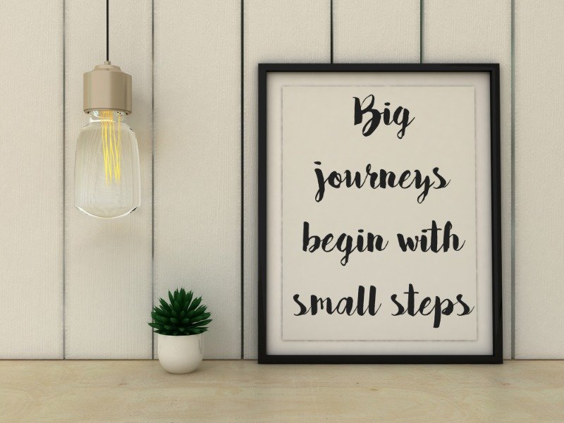 Framed quote saying "Big journeys begin with small steps" on a desk, providing a mindset shift for those learning how to start decluttering when overwhelmed